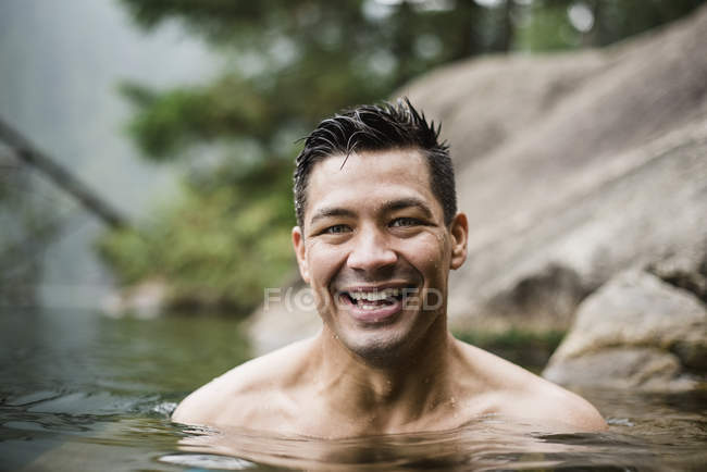 Porträt lächelnder, gutaussehender junger Mann, der im See schwimmt — Stockfoto