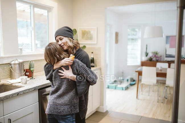 Affectionate mother and daughter hugging in kitchen — Stock Photo