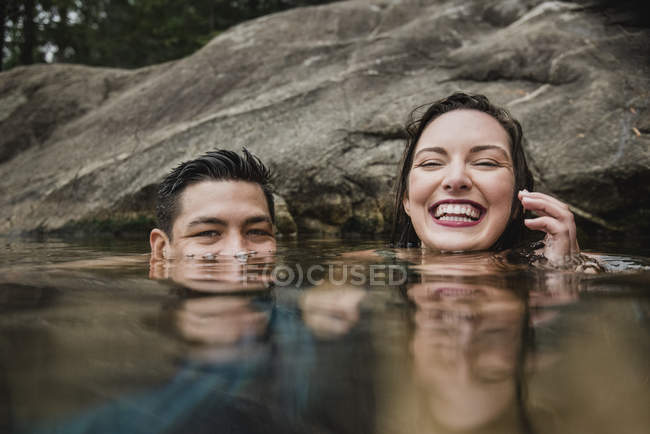 Ritratto giocoso giovane coppia nuotare nel lago — Foto stock