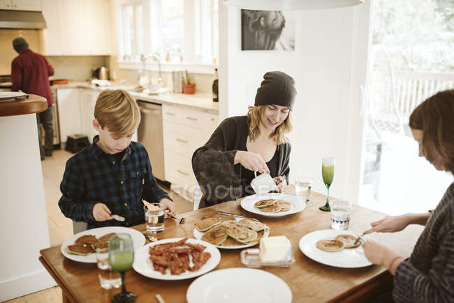 Petit déjeuner familial à la table de cuisine — Photo de stock