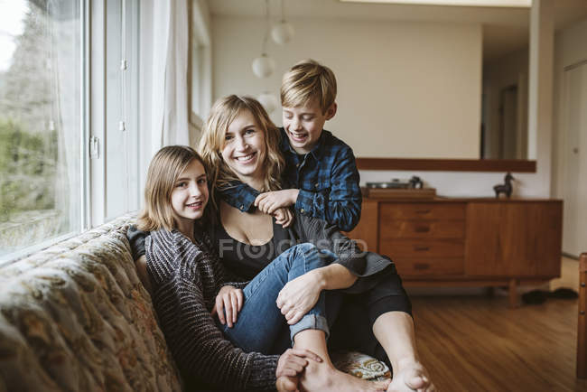 Retrato mãe feliz e crianças abraçando no sofá da sala de estar — Fotografia de Stock