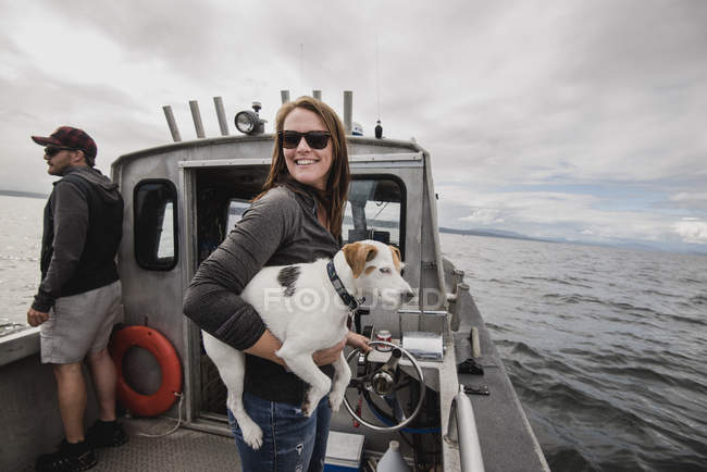 Portrait of smiling woman with dog on fishing boat — Stock Photo