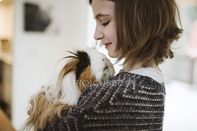 Girl holding cute, long haired guinea pig — Stock Photo