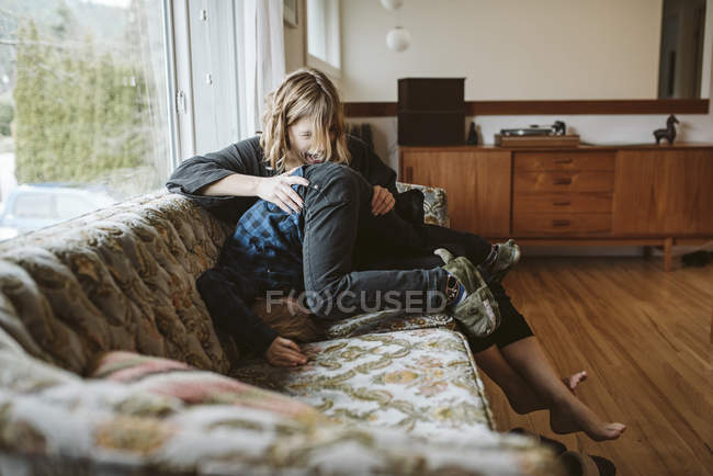 Игривая мать и сын на диване в гостиной — стоковое фото