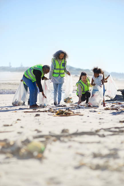 Добровольцы убирают мусор на солнечном песчаном пляже — стоковое фото