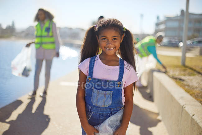 Portrait fille souriante bénévole nettoyer la litière sur la promenade ensoleillée — Photo de stock