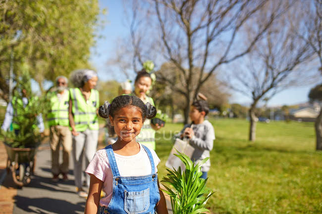 Porträt lächelnd, selbstbewusstes Mädchen, das sich freiwillig engagiert, Bäume im sonnigen Park pflanzt — Stockfoto