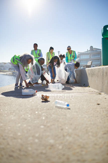 Добровольцы собирают пластиковый мусор на солнечной набережной — стоковое фото