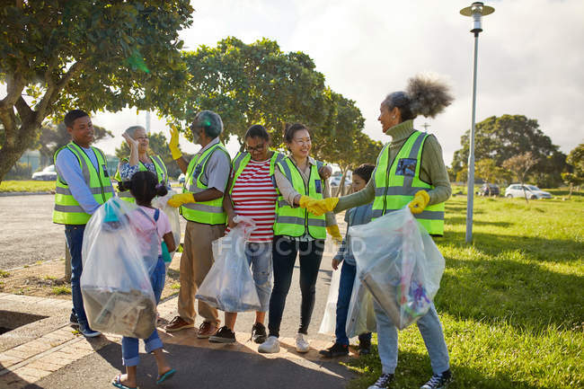 Happy volunteers celebrating, cleaning litter from sunny park — Stock Photo