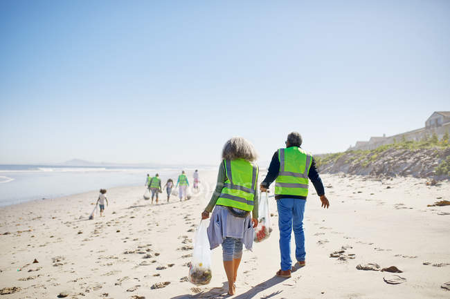 Volunteers cleaning up litter on sunny, sandy beach — Stock Photo