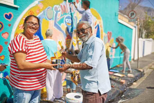 Портрет счастливые волонтеры сообщества рисуют фрески на солнечной городской стене — стоковое фото