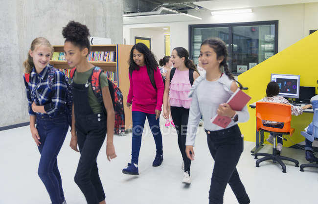 Junior high girl students walking in library — Stock Photo