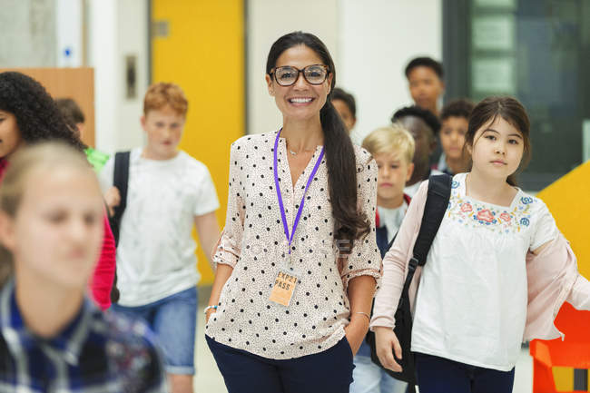Junior high students walking around smiling female teacher — Stock Photo