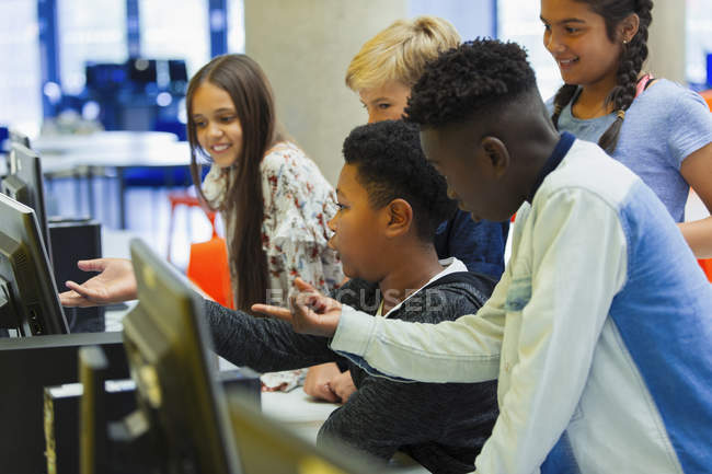 Junior high students using computer in library — Stock Photo