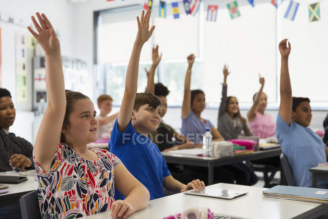 Alunos ansiosos do ensino médio com as mãos levantadas na sala de aula — Fotografia de Stock