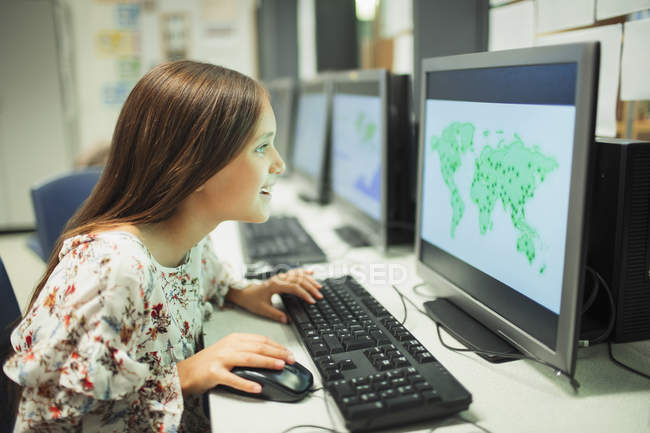 Estudante curioso do ensino fundamental olhando para o mapa no computador em sala de aula — Fotografia de Stock