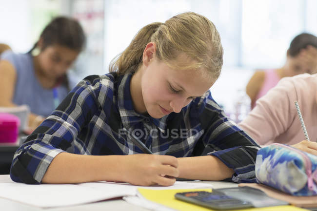 Estudiante de secundaria enfocado haciendo tarea en el aula - foto de stock