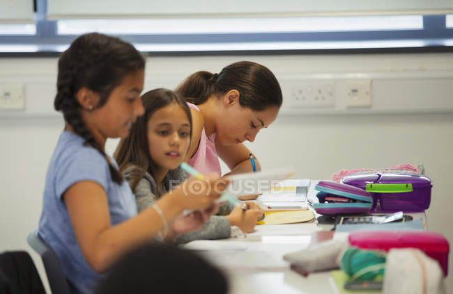 Estudiantes de secundaria estudiando en el escritorio en el aula - foto de stock