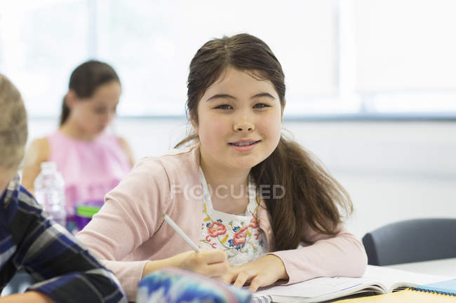 Portrait confident junior high school girl student doing homework in classroom — Stock Photo