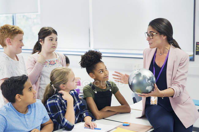 Attentive junior high school students watching geography teacher with globe — Stock Photo