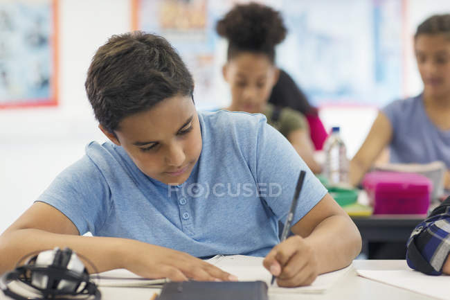 Junior high school boy student doing homework in classroom — Stock Photo