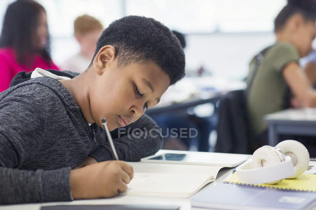Junior high school boy student doing homework in classroom — Stock Photo