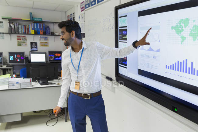 Männlicher Lehrer leitet Unterricht am Bildschirm im Klassenzimmer — Stockfoto