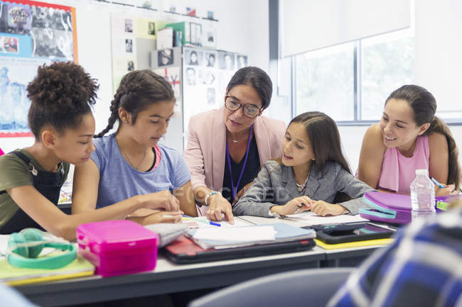 Lehrerin und Realschüler lernen am Schreibtisch im Klassenzimmer — Stockfoto