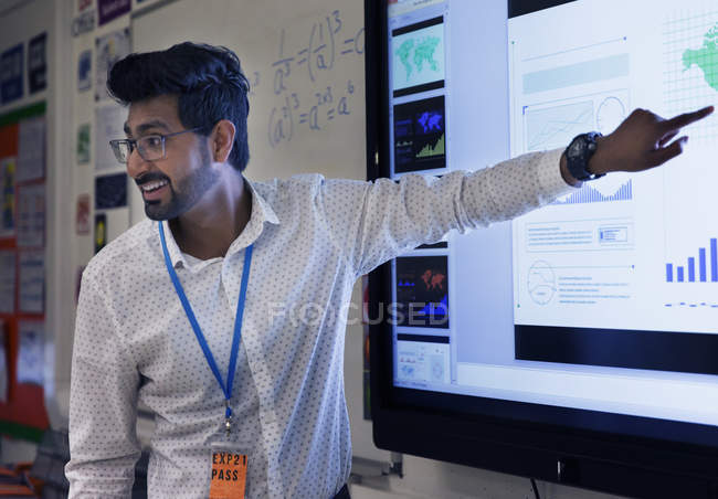 Smiling male teacher leading lesson at touch screen in classroom — Stock Photo