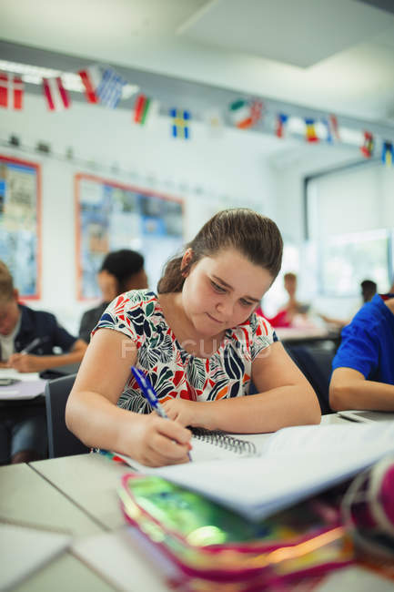 Фокусована молодша школярка робить домашнє завдання за столом у класі — стокове фото