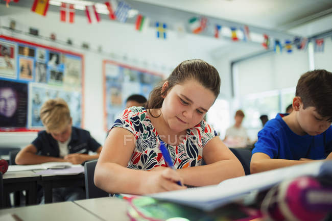 Сосредоточенный ученица средней школы делает домашнее задание в классе — стоковое фото
