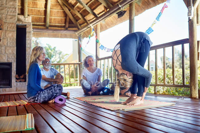 Female yoga instructor demonstrating forward fold in hut during yoga retreat — Stock Photo