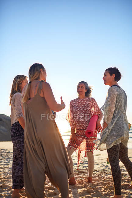 Women with yoga mats talking on sunny beach during yoga retreat — Stock Photo