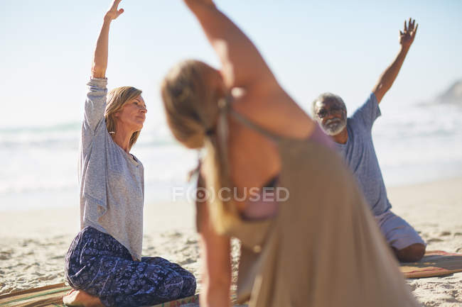 Gruppe dehnt sich am sonnigen Strand während des Yoga-Retreats — Stockfoto