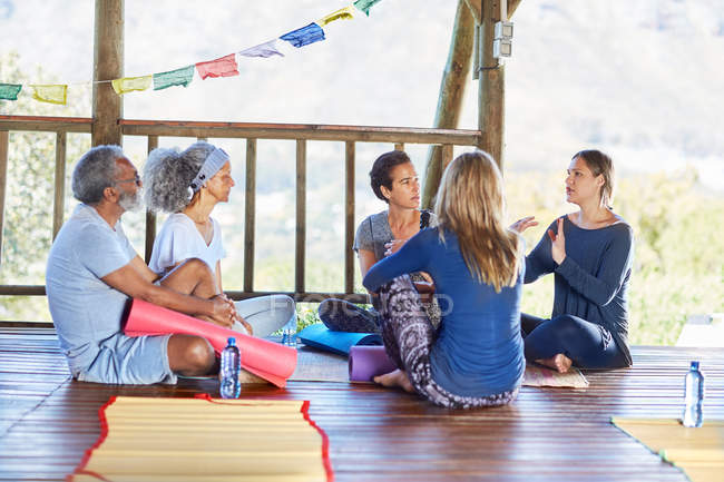 Clase de yoga hablando en círculo en cabaña durante retiro de yoga - foto de stock