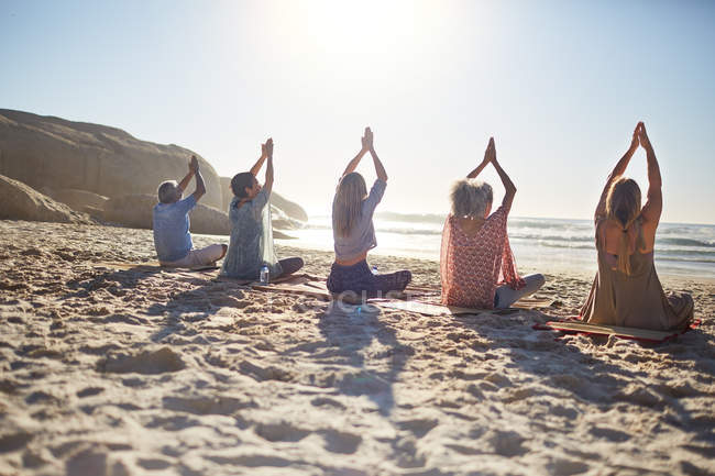 Группа практикующих йогу на солнечном пляже во время йоги отступления — стоковое фото