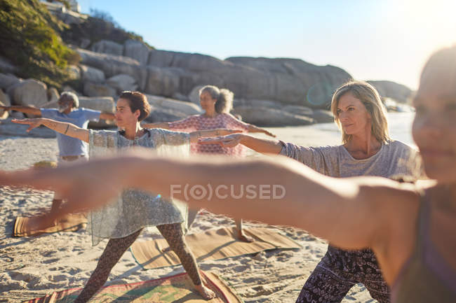 Группа практикующих йогу на солнечном пляже во время йоги отступления — стоковое фото