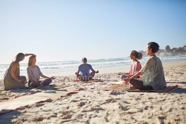 Gruppe meditiert am sonnigen Strand während des Yoga-Retreats — Stockfoto