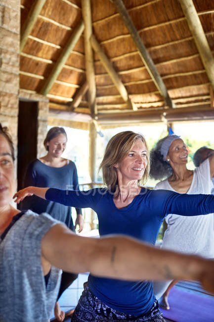 Mujer confiada practicando la pose guerrera 2 en la cabaña durante el retiro de yoga - foto de stock