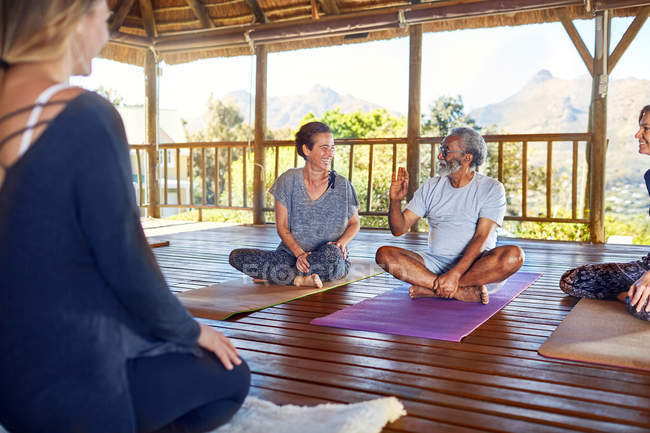 Hombre y mujer hablando durante clase de yoga en cabaña en retiro de yoga - foto de stock