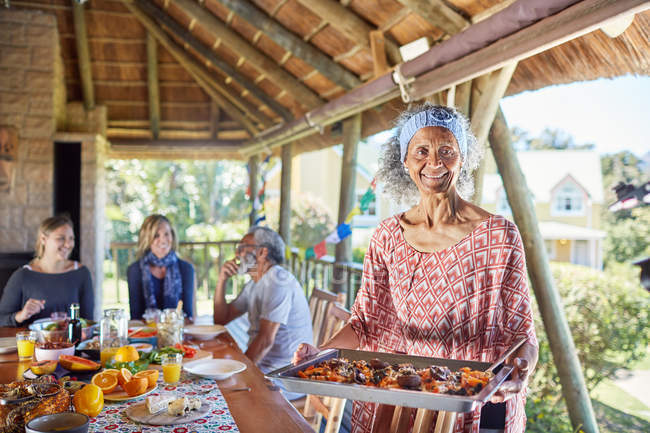 Portrait smiling senior woman serving food to guests in hut — Stock Photo