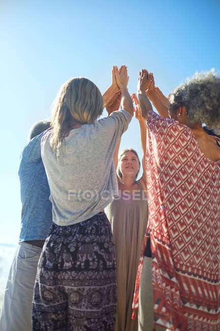 Grupo de pie en círculo con los brazos levantados durante retiro de yoga - foto de stock