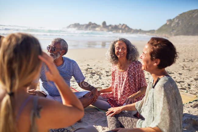 Друзья сидят в кругу на солнечном пляже во время йоги отступления — стоковое фото