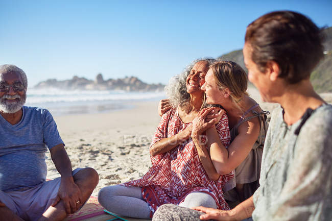 Щасливі жінки обіймаються на сонячному пляжі під час відступу йоги — стокове фото