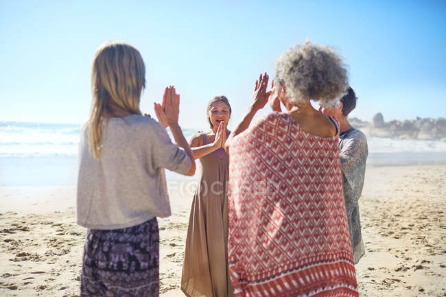 Mulheres amigas com as mãos fechadas em círculo na praia ensolarada durante retiro de ioga — Fotografia de Stock