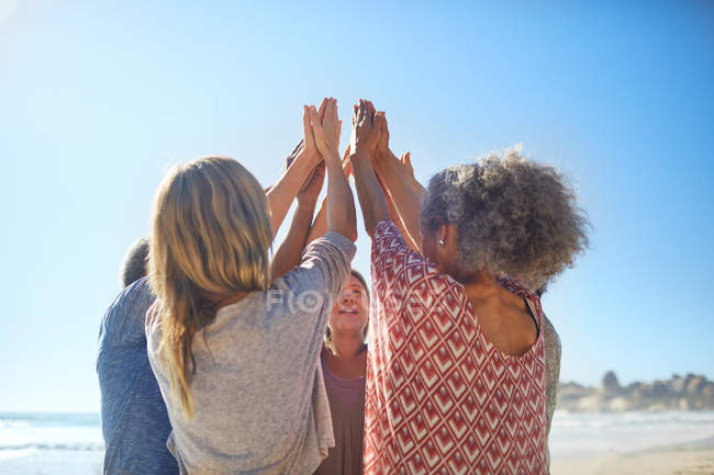 Жінки друзі піднімають руки в колі під час відступу йоги на сонячному пляжі — стокове фото