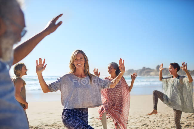 Baile en grupo en la playa soleada durante el retiro de yoga - foto de stock