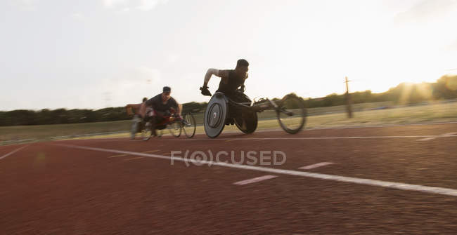 Athlètes paraplégiques accélérant le long de la piste sportive pendant la course en fauteuil roulant — Photo de stock