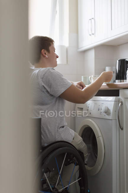 Jeune femme en fauteuil roulant préparer le thé dans la cuisine appartement — Photo de stock