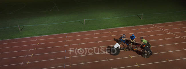 Паралитические спортсмены собираются на спортивной трассе, тренируются для забега на инвалидных колясках ночью — стоковое фото